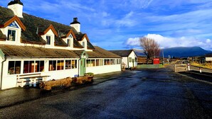 A traditional building with a white facade, multiple chimneys, and a sign indicating it is a pub. - Aultguish Inn (Garve)