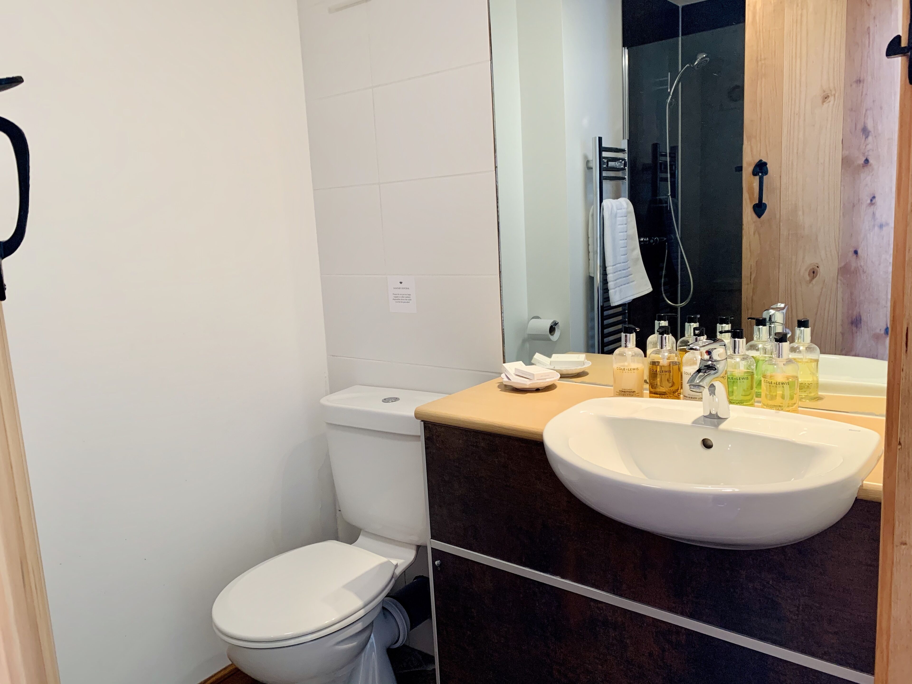 Ein Badezimmer mit einer weißen Toilette, einem Waschbecken mit Spiegel darüber und Toilettenartikeln auf dem Waschbecken.