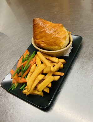 A meal consisting of a pie, French fries, and green beans on a black plate.