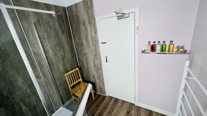 A room with a wooden chair, a white door, and a shelf with bottles. - Aultguish Inn (Garve)