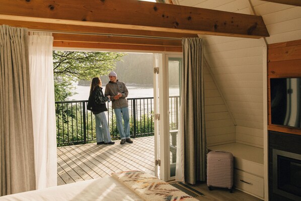 Una habitación con cama, maleta y balcón con vistas.