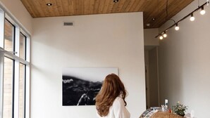 Un interior moderno con un mostrador de recepción de madera, un gran cuadro abstracto y una escultura de madera original.