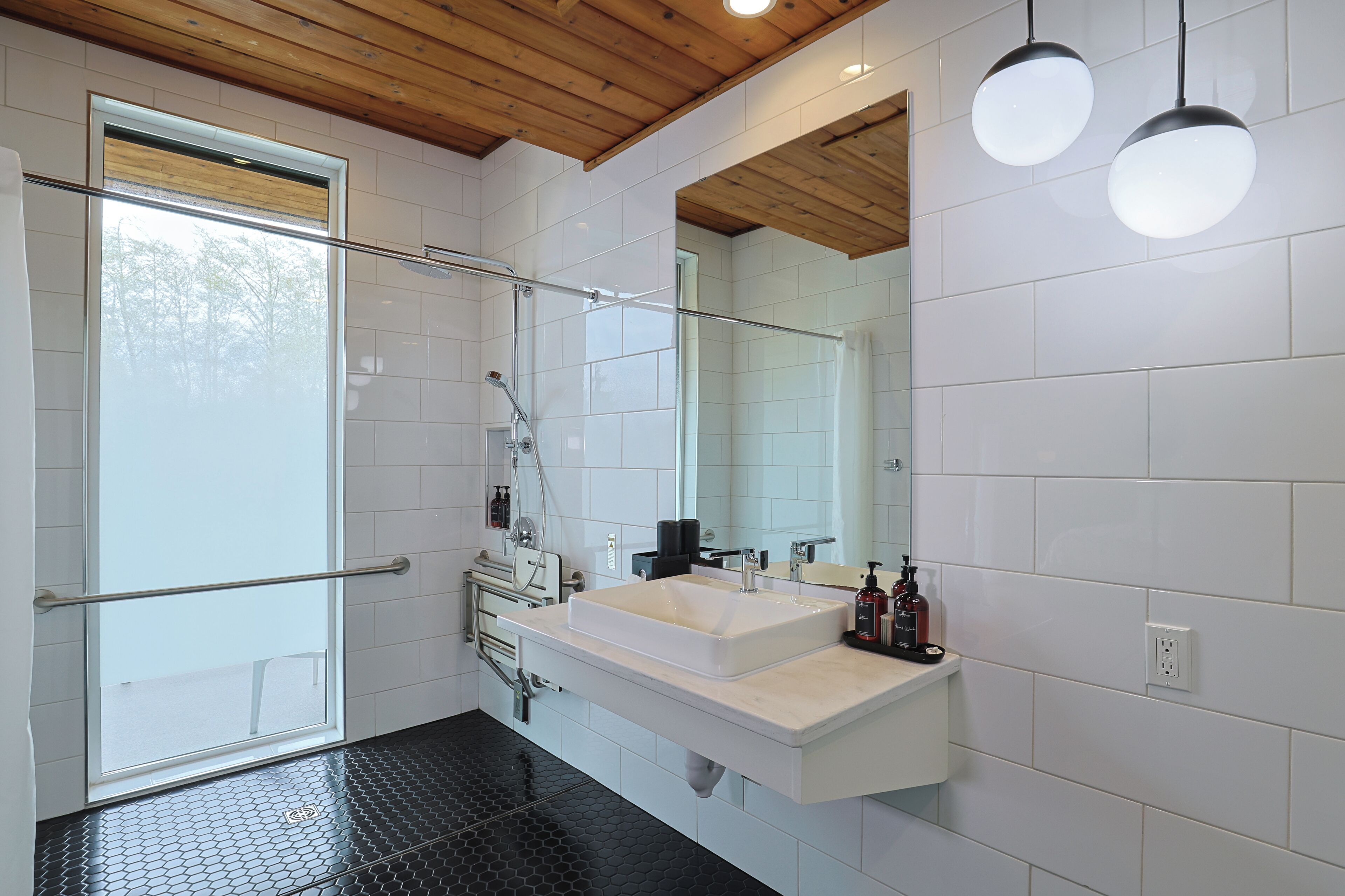 A modern bathroom with a large mirror, a white sink, and a shower area.