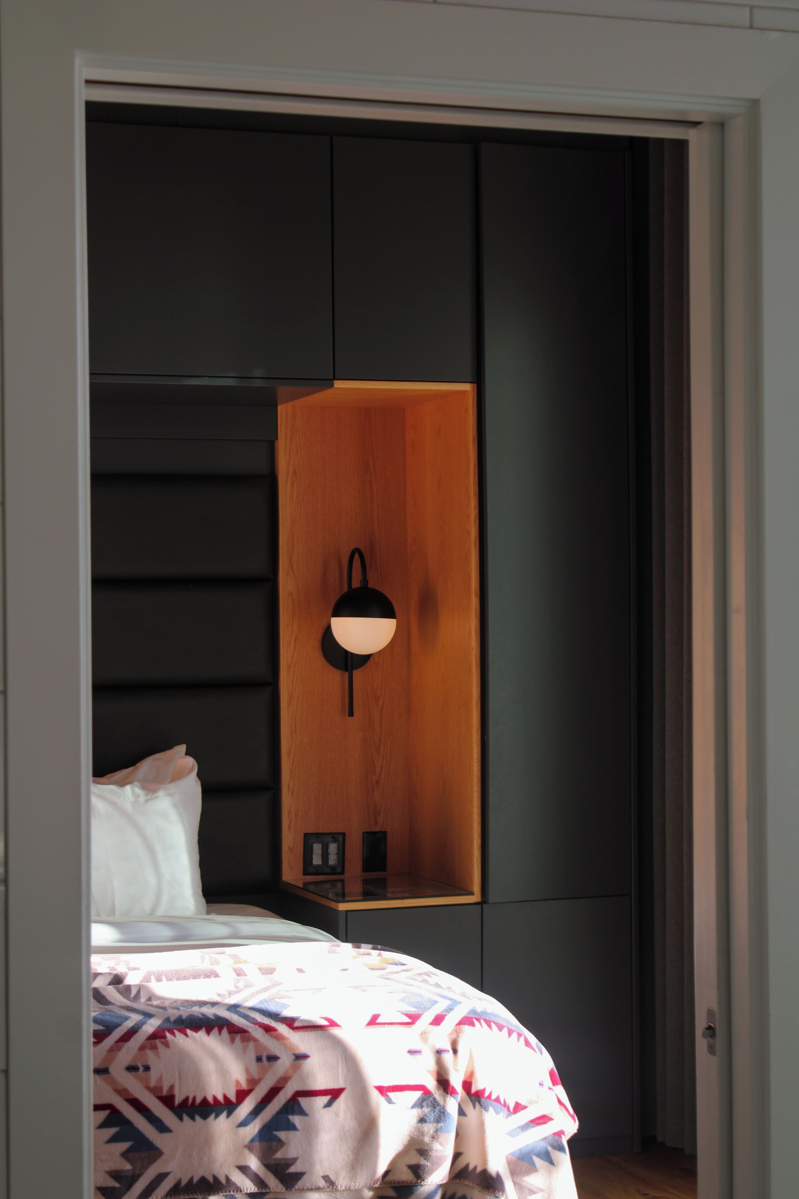 Un dormitorio con una cama, un armario de madera y una lámpara de pared.