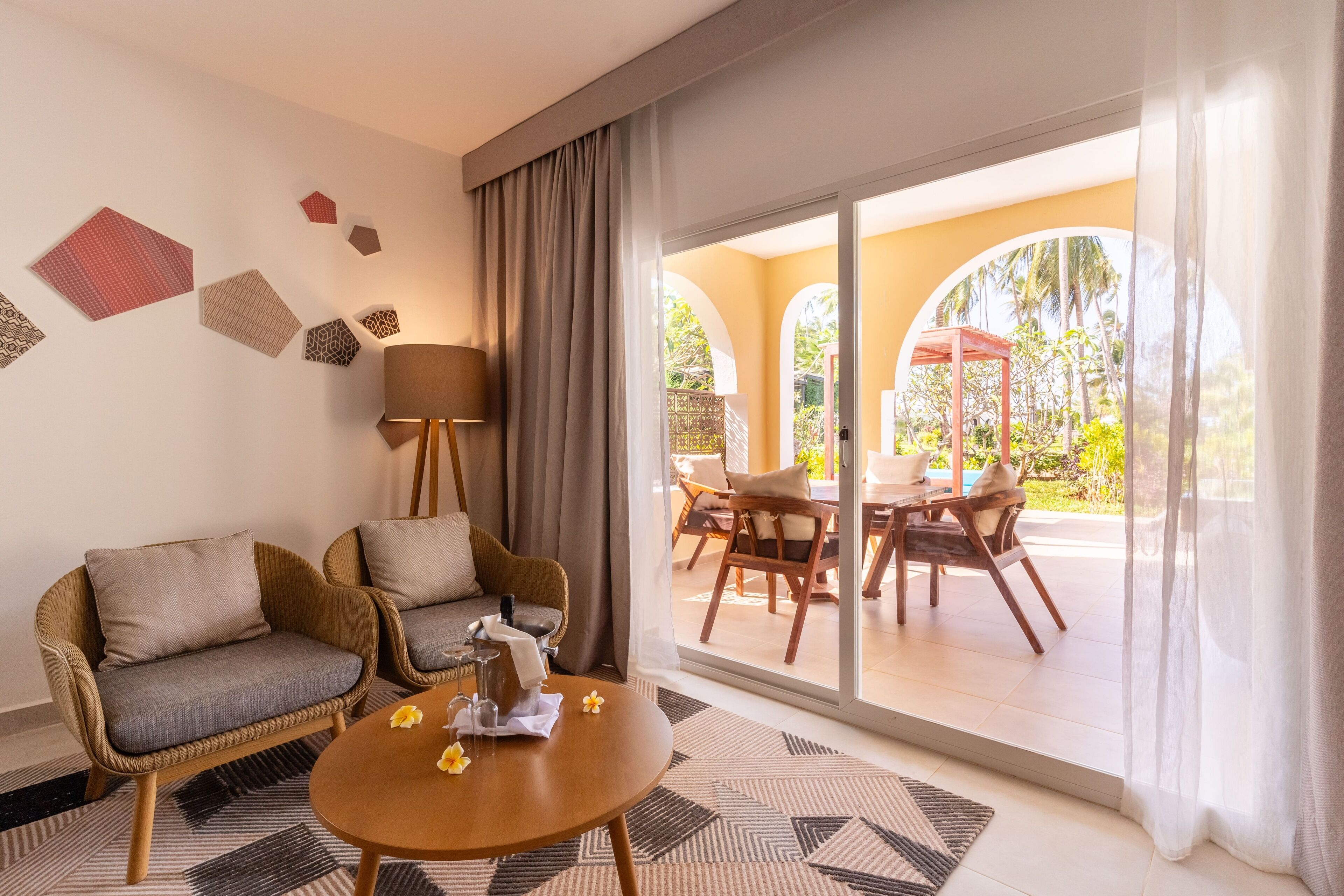 A room with a sofa, a coffee table, and a view of an outdoor patio with chairs and a table.