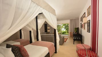 A bedroom with two beds, a sofa, a TV, and a balcony with a view of greenery.