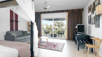 A hotel room with a balcony, a sofa, a TV, and a bed.