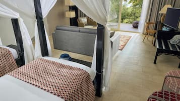 Ein Hotelzimmer mit Bett, Sofa, Fernseher und Blick ins Freie.