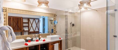 A modern bathroom with a glass-enclosed shower, a large mirror, and a wooden vanity.
