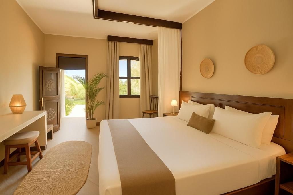 A hotel room with a bed, desk, chair, and a view of the outdoors.