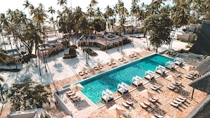 A resort with a central swimming pool surrounded by lounge chairs and umbrellas, palm trees, and a sun terrace. - Diamonds Mapenzi Beach (Kiwengwa)