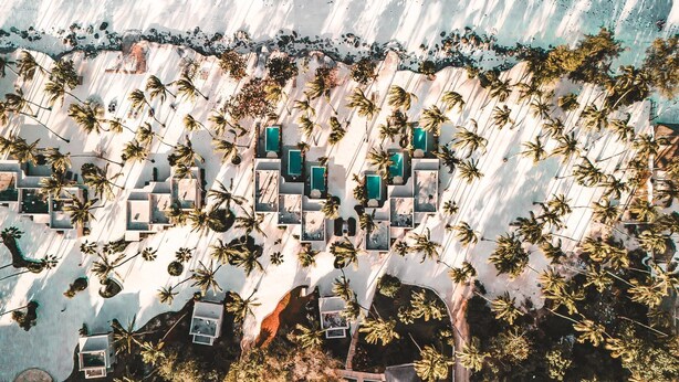 An aerial view of a resort with multiple swimming pools, palm trees, and a beach area. - Diamonds Mapenzi Beach (Kiwengwa)