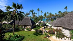 A resort with thatched-roof huts, a well-maintained garden, and a view of the ocean. - Diamonds Mapenzi Beach (Kiwengwa)