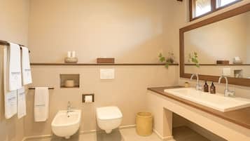 A modern bathroom with a bidet, toilet, sink, and a large mirror.