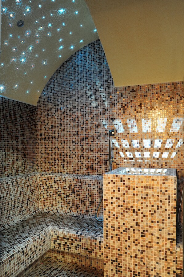 A room with mosaic tile walls and ceiling, a built-in bench, and a shower area. - Lunetta Hotel & SPA (Rome)