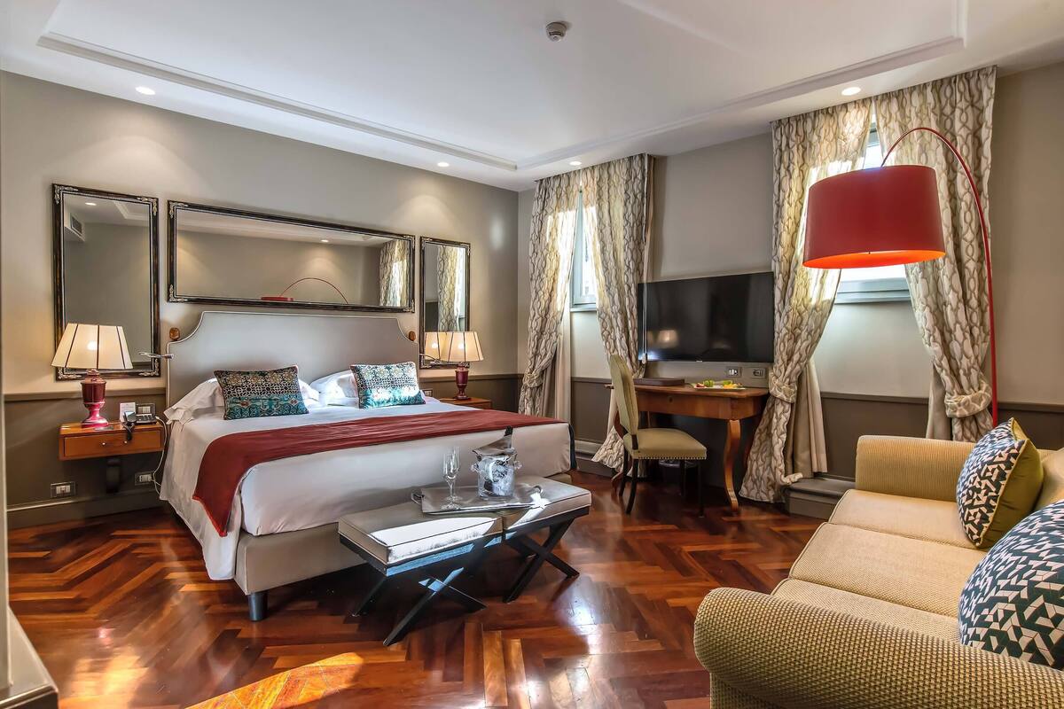 A hotel room with a bed, a desk, a TV, and a sofa.