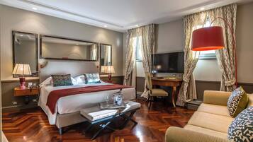 Una habitación de hotel con cama, escritorio, televisor y sofá.