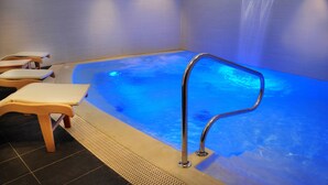 Een wellnessruimte met een whirlpool, houten stoelen en een douche.