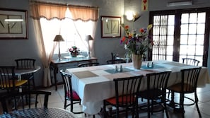 A dining area with a long table, chairs, a vase with flowers, and framed pictures on the walls. - Villa Via - Midrand (Midrand)