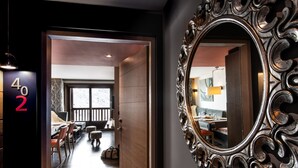 Ein Hotelzimmer mit Holzboden, einer Essecke mit Tisch und Stühlen und einem großen, verzierten Spiegel an der Wand.