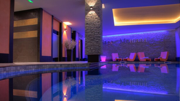 Ein moderner Poolbereich im Innenbereich mit einer Steinwand und Liegestühlen.
