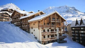 Ein Chalet-Hotel aus Holz mit mehreren Balkonen und Blick auf die Berge.