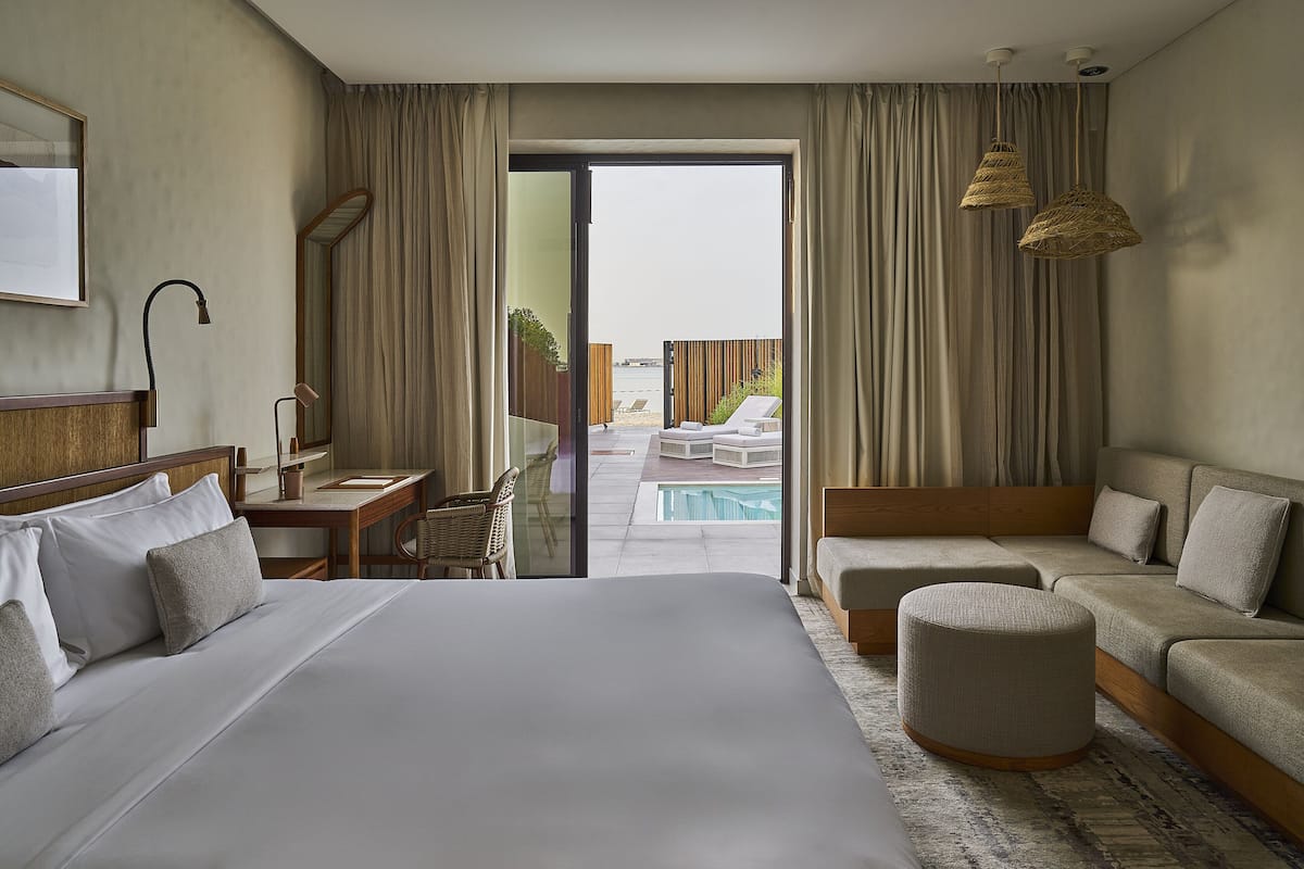 Ein Hotelzimmer mit einem großen Bett, einem Schreibtisch, einer Couch und Blick auf Pool und Strand.