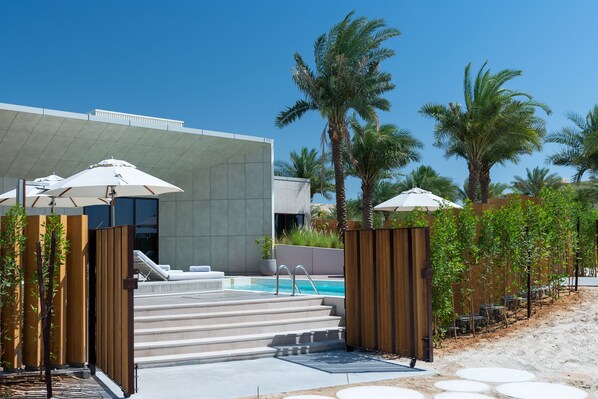 A modern resort with a swimming pool, wooden gates, and palm trees. - ERTH Abu Dhabi Hotel (Abu Dhabi)