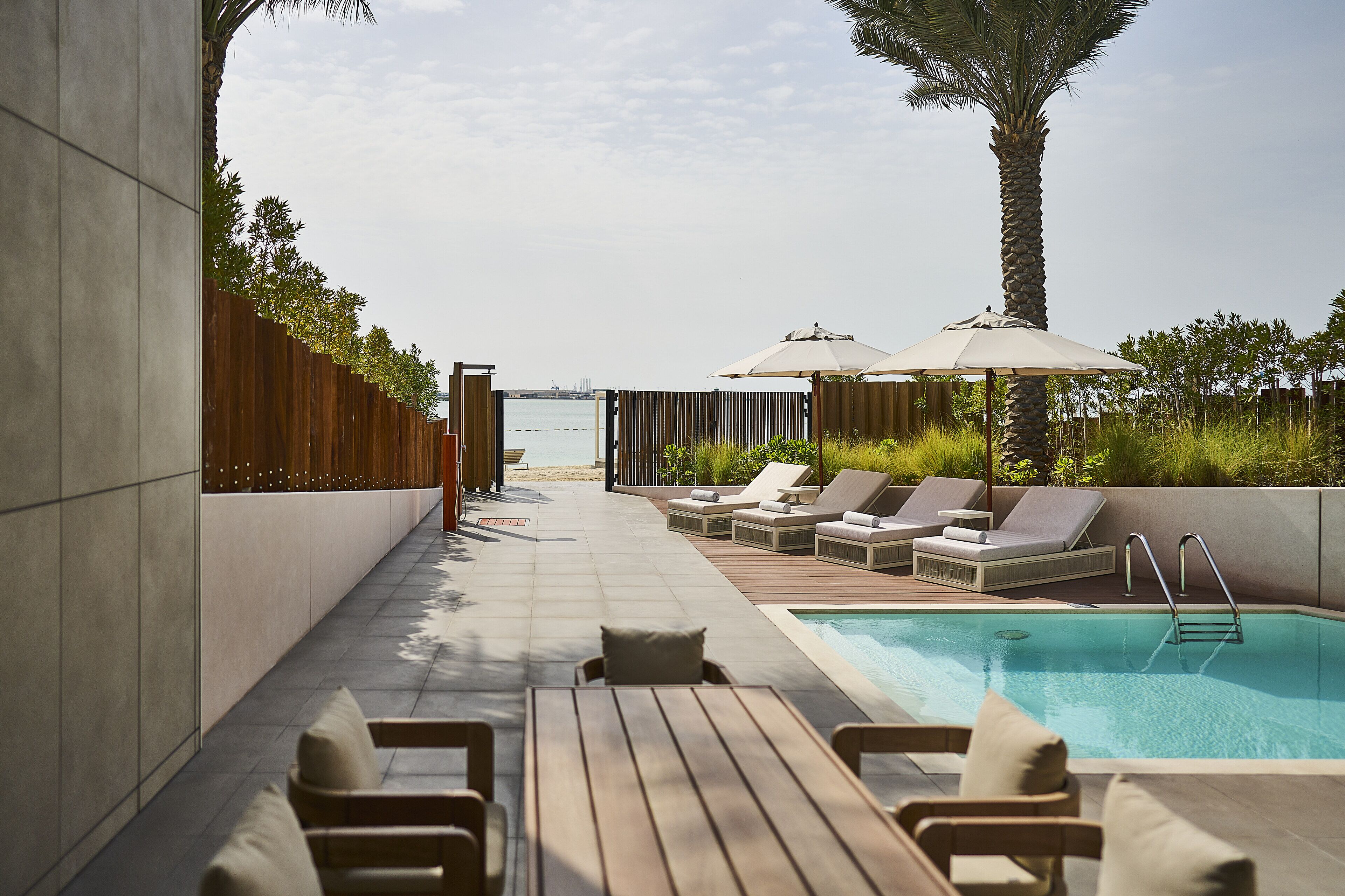 Un área de piscina en la azotea con sillones, una piscina y vistas al mar.
