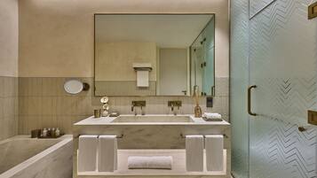 A modern bathroom with a large mirror, two sinks, a bathtub, and a glass shower enclosure.