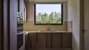 A compact kitchen with a window, built-in oven, and dark wooden cabinets.