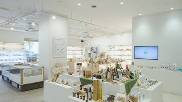 A clean, well-lit store with various products on display, including bottles and boxes, and a television screen on the wall.