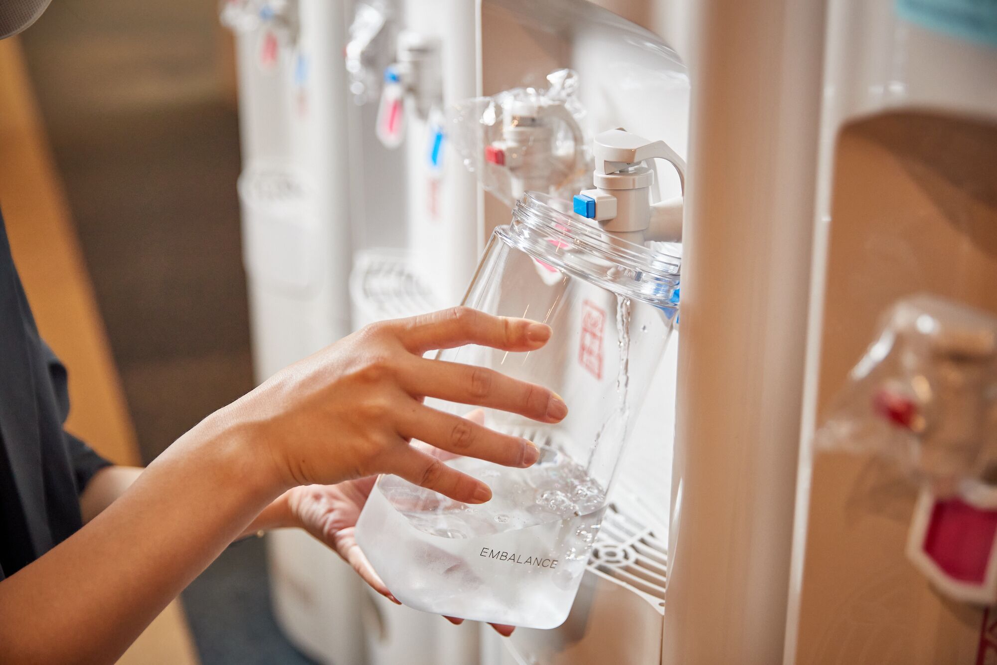 A person filling a water bottle from a dispenser.