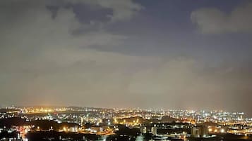 Une vue nocturne d’une ville, avec des bâtiments illuminés et un ciel nuageux.