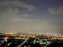 Paisagem urbana noturna com edifícios iluminados e um céu nublado.