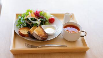 A tray with a plate of toasted bread, a salad, a small bowl of sauce, and a cup of tomato soup.