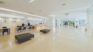 Een ruime lobby met een receptiebalie, een zithoek en een modern design.