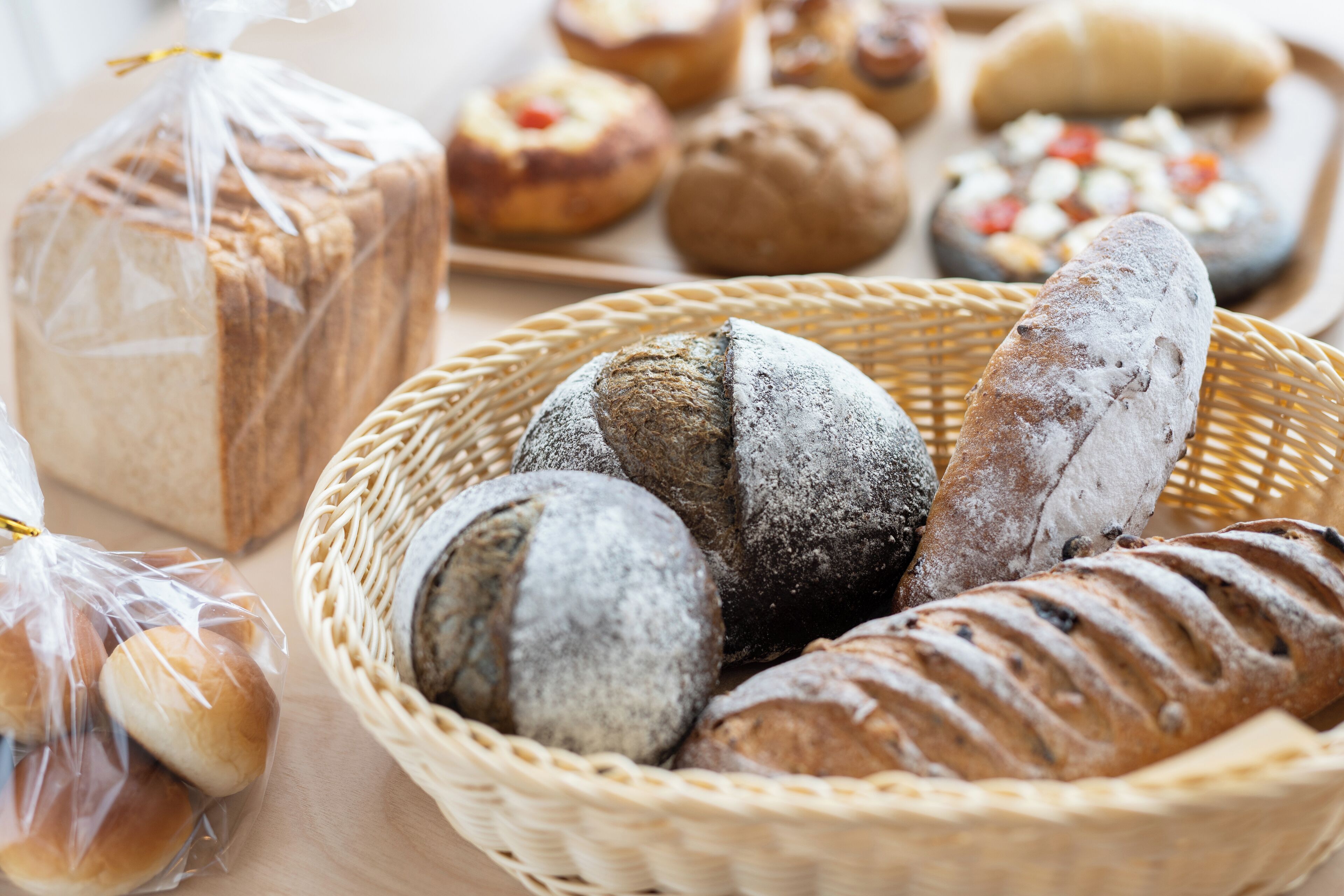 Una cesta con panes y pasteles varios, incluyendo una barra de pan y una baguette.
