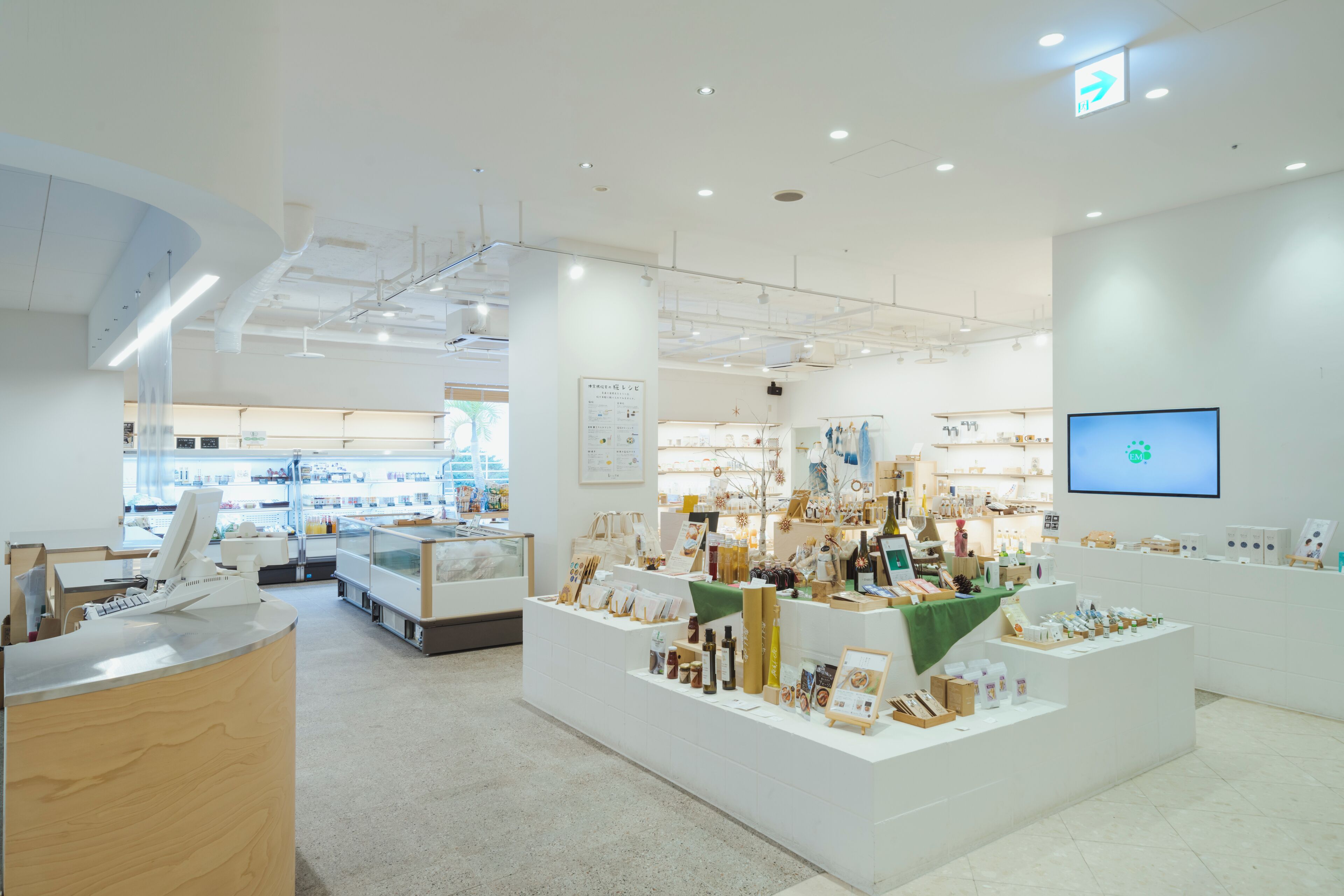 A modern, well-lit store with white walls and a clean layout, featuring various products on display.