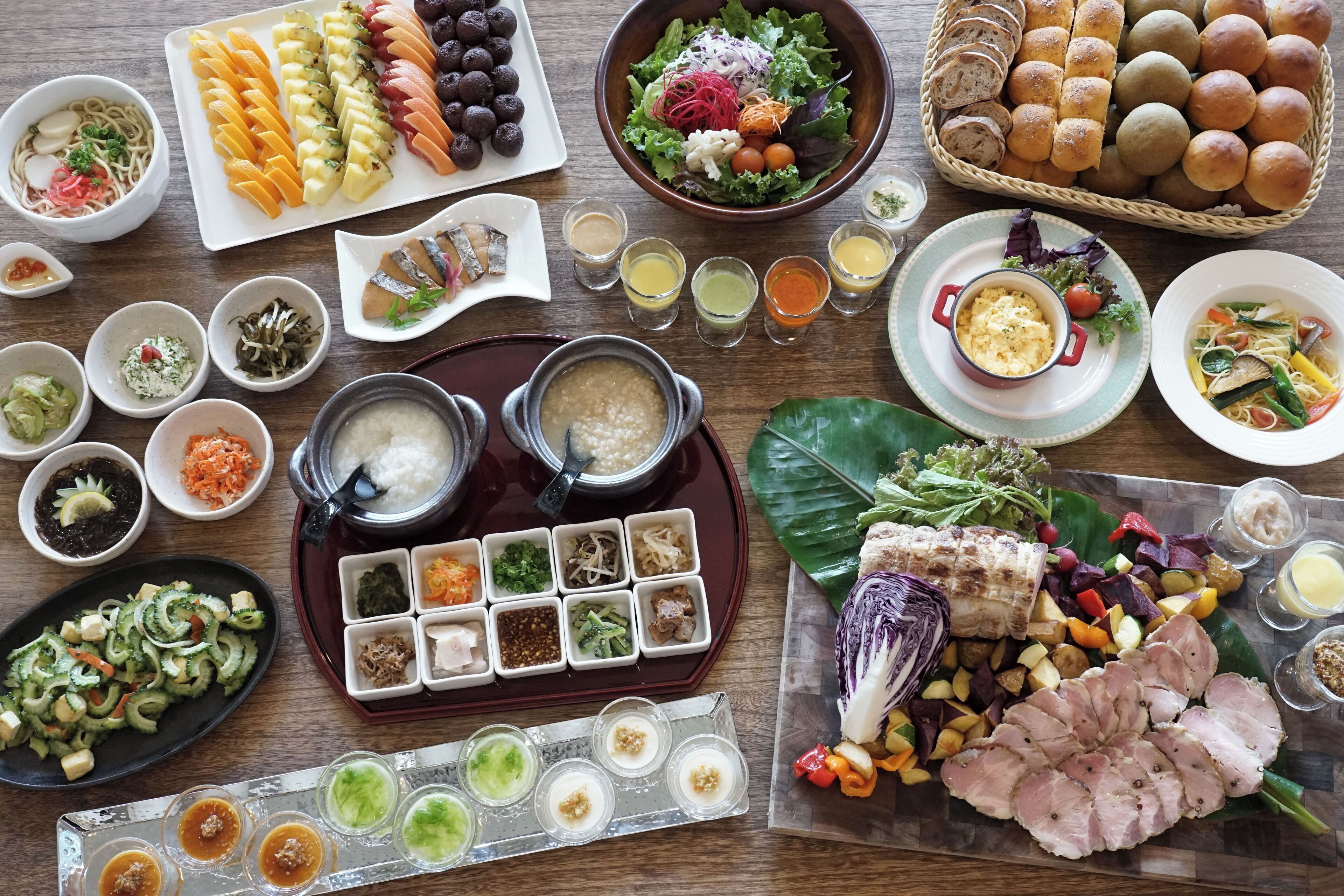 Verschiedene Gerichte und Beilagen sind auf einem Holztisch angerichtet, darunter Sushi, Gemüse und Fleisch.