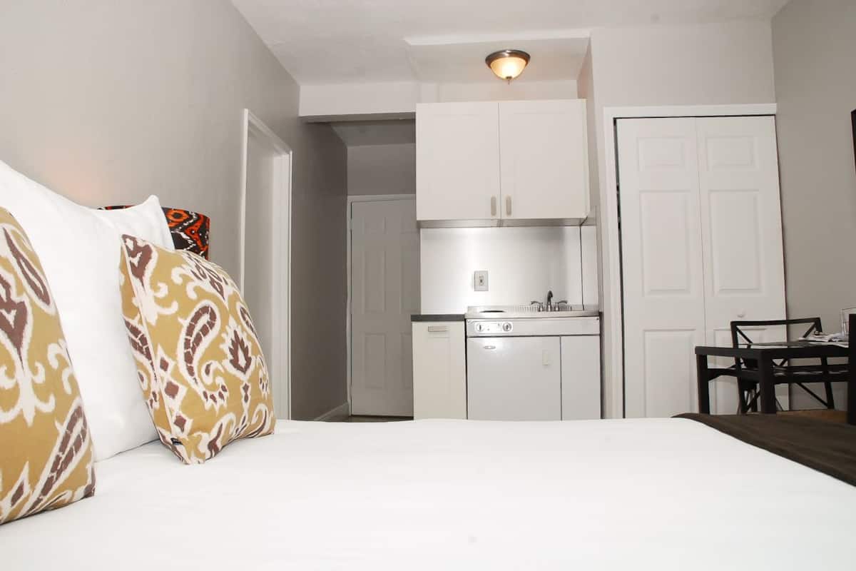 A compact room with a bed, a kitchenette, and a dining area.