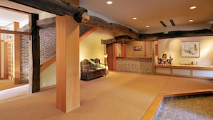 Amplia habitación con vigas de madera a la vista, pared de ladrillo y un espacio para ceremonia del té japonesa tradicional.