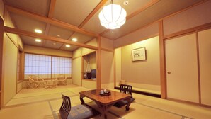 Una habitación tradicional japonesa con suelo de tatami, una mesa de madera baja y un ventilador de techo.