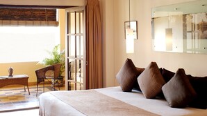 Een hotelkamer met een groot bed, een stoel, een klein tafeltje en een potplant.