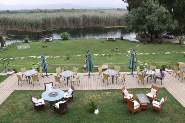 Una terraza con mobiliario exterior, un estanque y vistas a un paisaje natural.