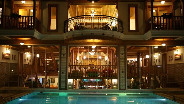 Una amplia piscina interior con una zona de bar central, varios balcones y una imponente escalera.