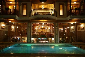 Una amplia piscina interior con una zona de bar central, varios balcones y una imponente escalera.