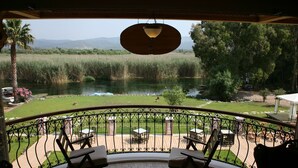 Un balcón con vista a un río, rodeado de vegetación y un cielo despejado.