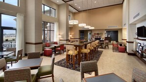 A spacious hotel lobby with multiple seating areas, a long communal table, and large windows offering views. - Hampton Inn & Suites Charles Town (Charles Town)