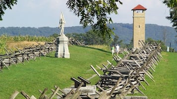 Un sitio histórico con una cerca de madera, un monumento de piedra y una torre al fondo.